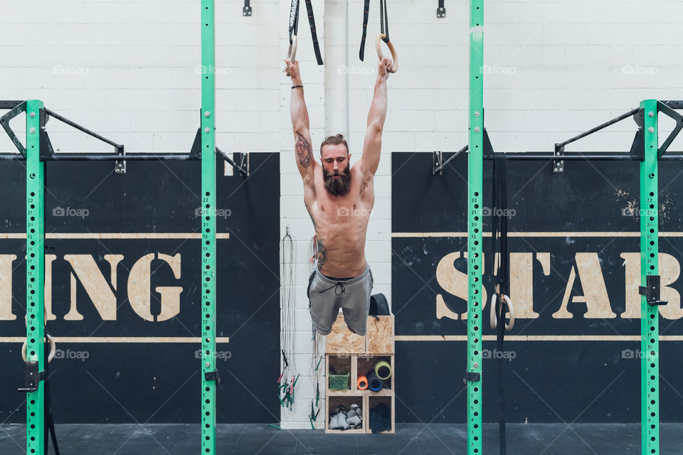 handsome bearded man working out at the gym doing pull up - fitness, sport, power