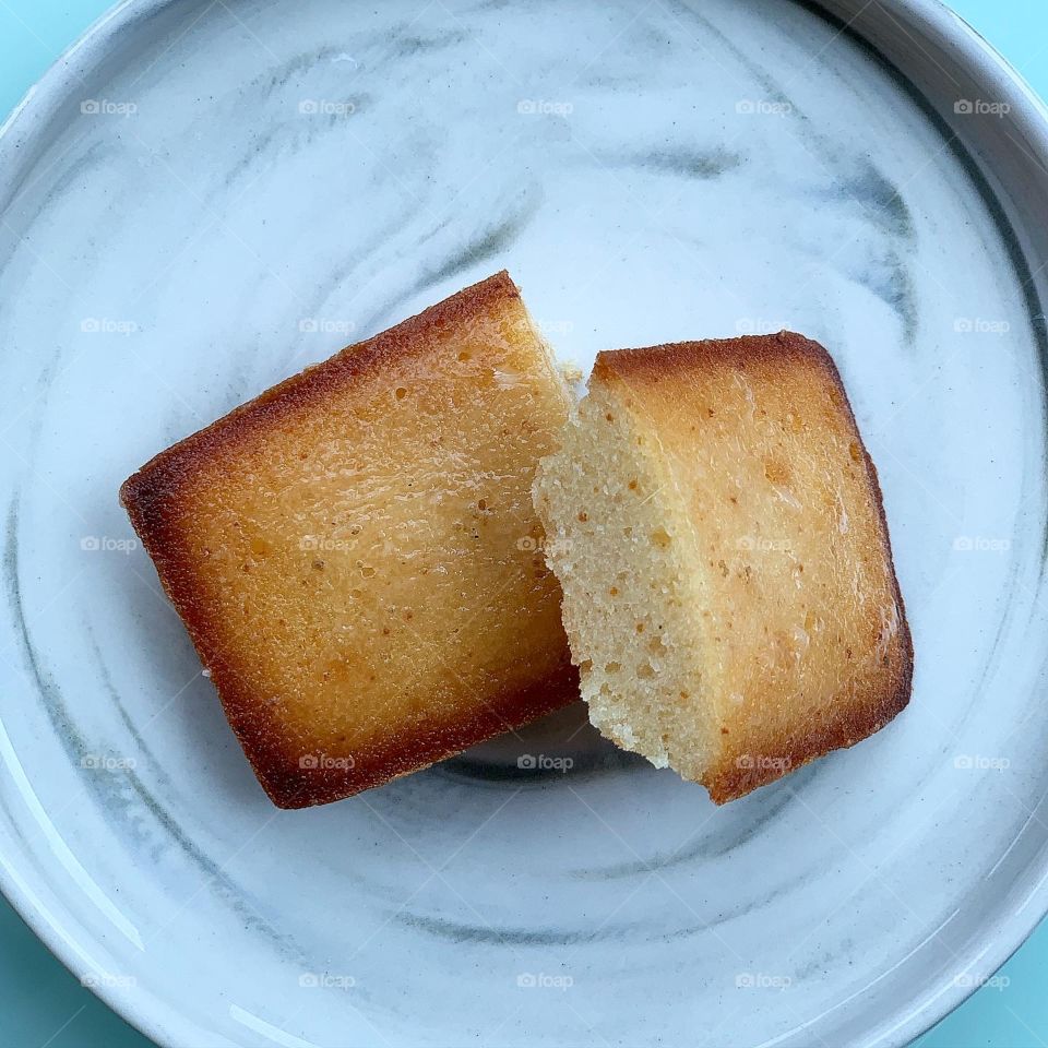 French patisserie financiers in four different flavours - brown butter, dark chocolate, black sesame and yuzu against a natural background 