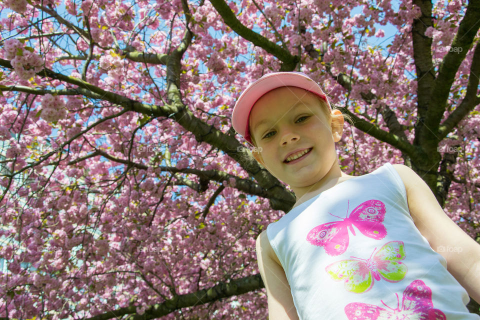 Young girl is playing in the park under a cherry blossom tree in Malmö Sweden.