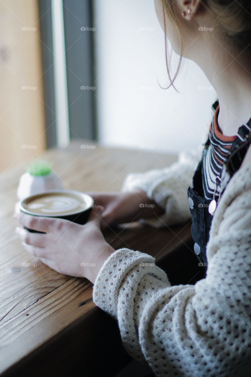 Women sitting at the window enjoying a latte in the early morning light at a coffee shop. 