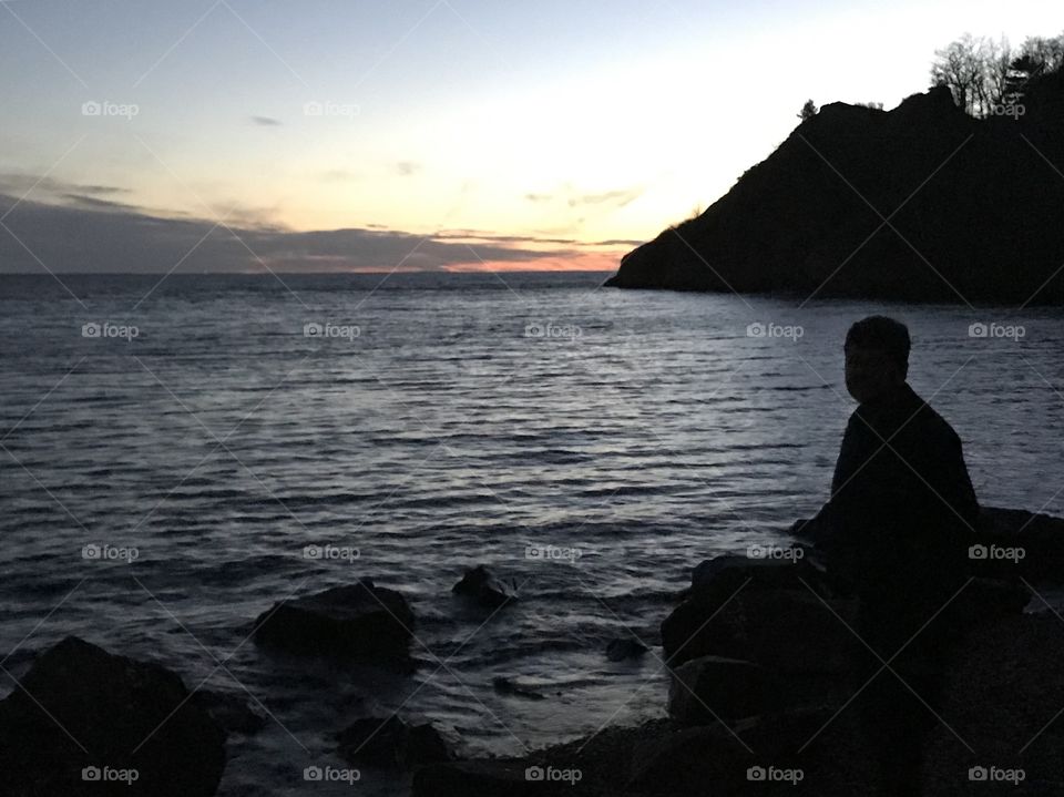 Man watching the sunset over water