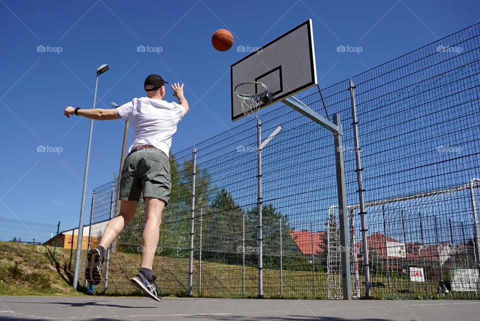 Man throw the ball in basketball basket