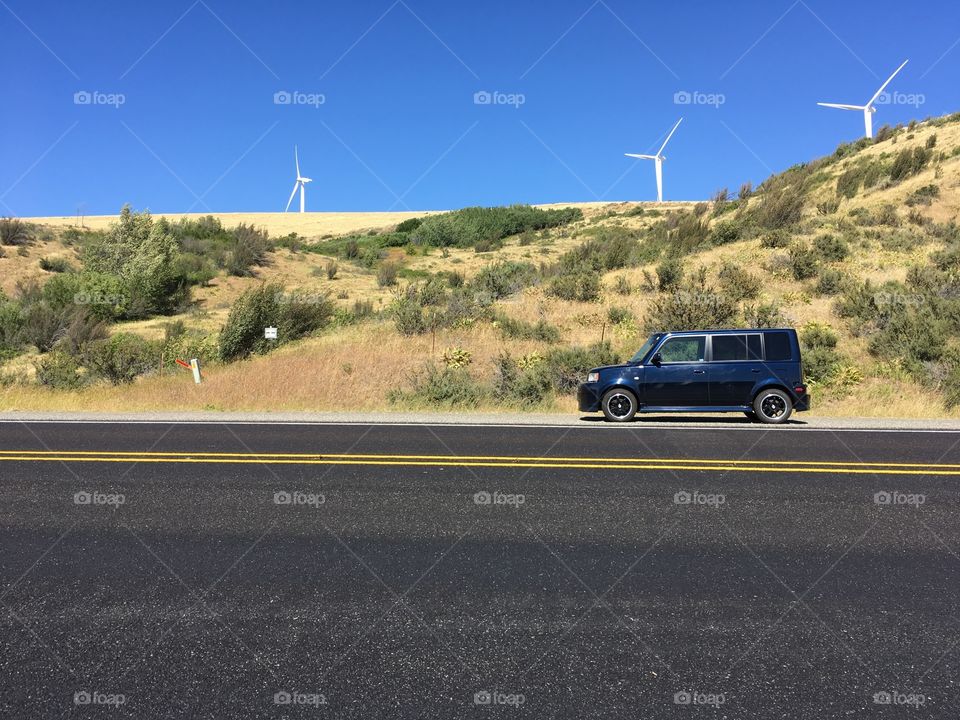 Car by the side of the road with windmills 