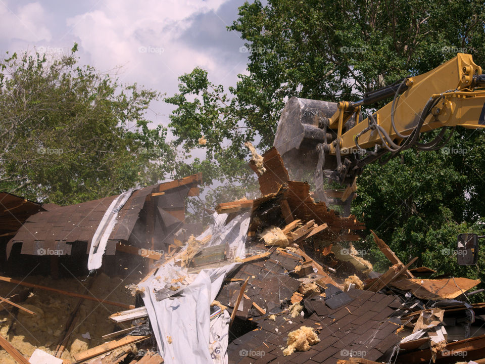Pile of Debris Building Up while an Excavator Demolishes a Storm Damaged Home