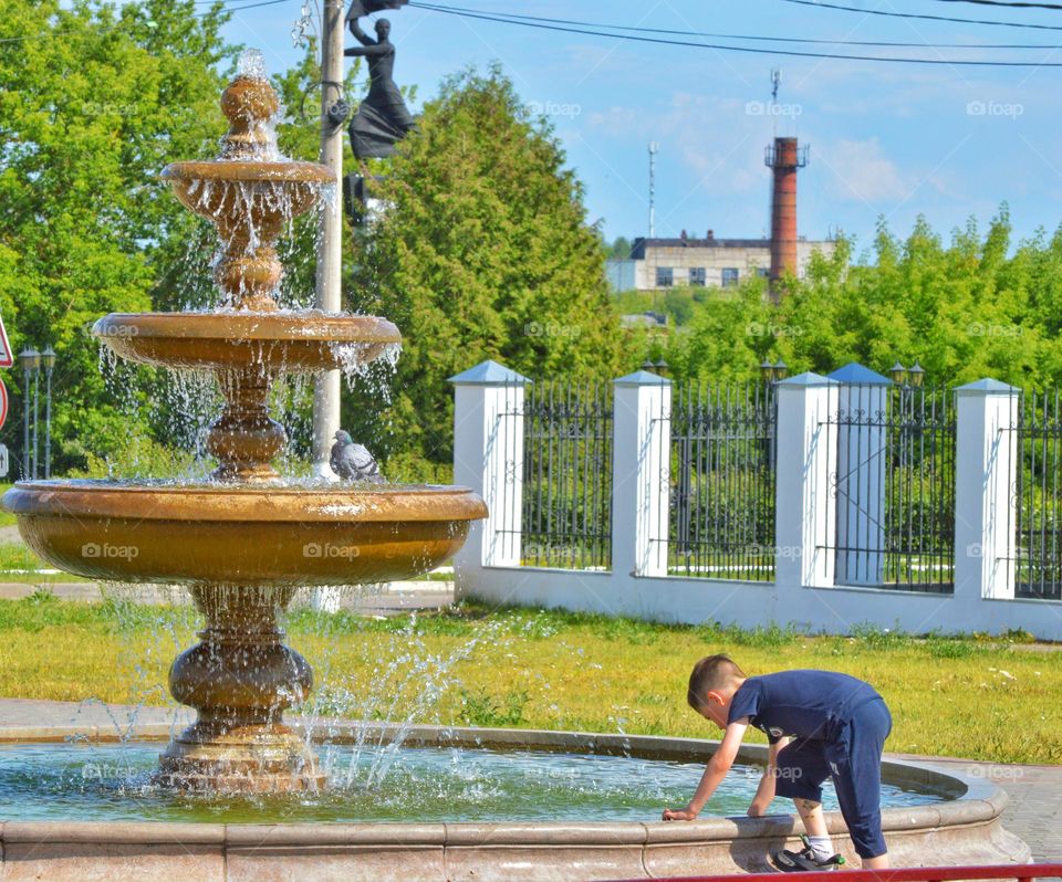 Gogorod fountain and a boy against the background of a monument of trees and a plant