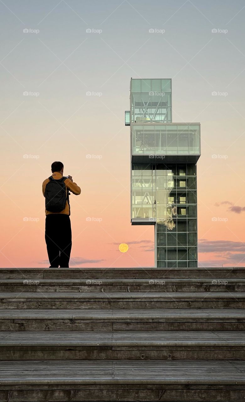 Man taking a picture of a rising full moon
