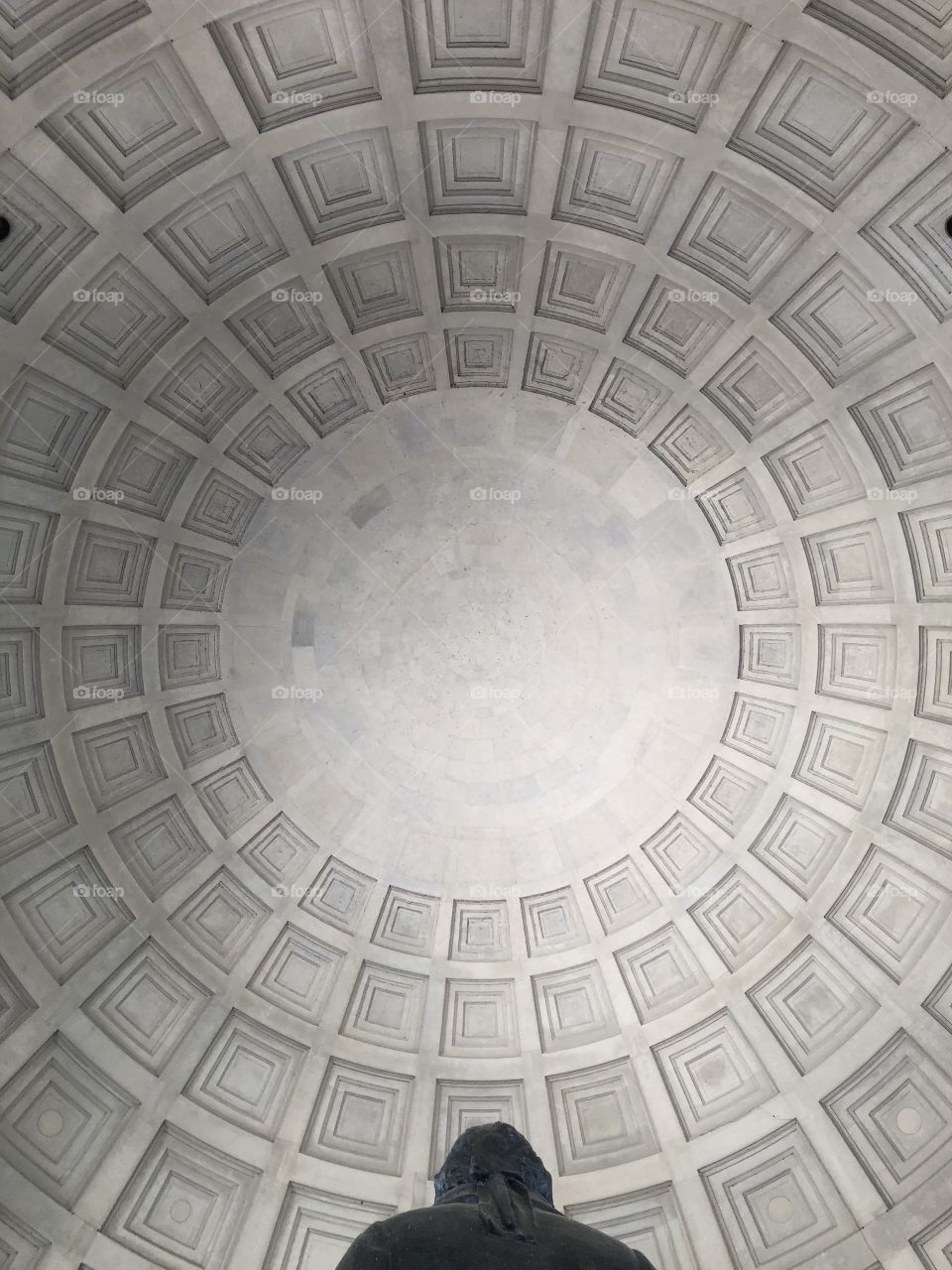 Natural light illuminates the decorative marble ceiling of the dome of a monument