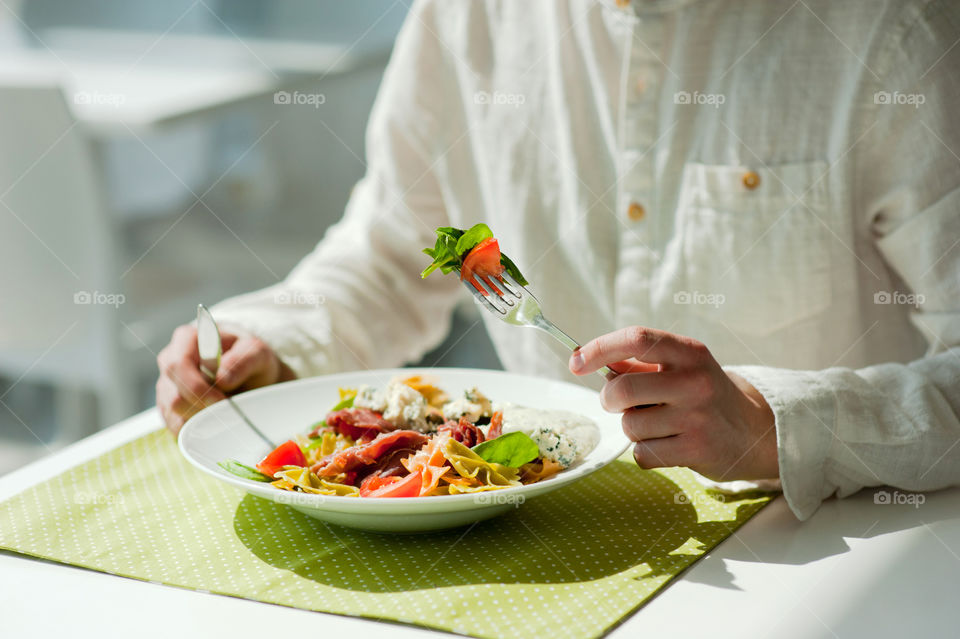 close-up of a young man eating a salad in a light kitchen