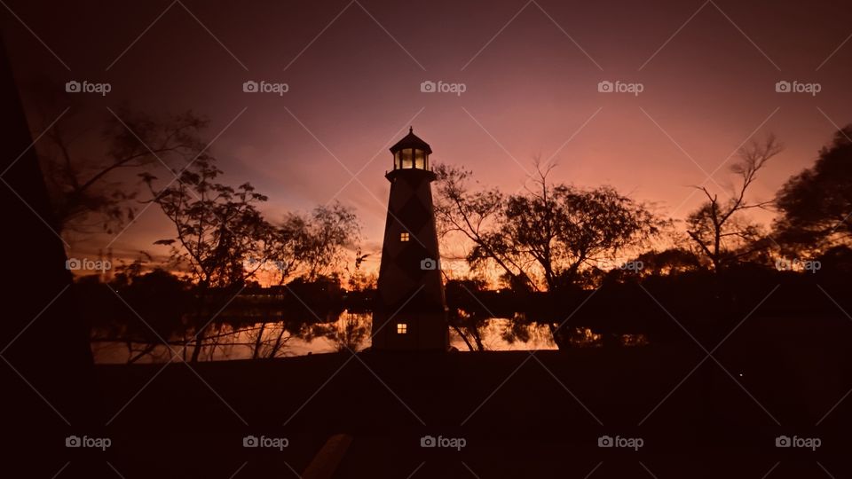 Lighthouse on North Shore hidden with trees peaking out with Reflections over water presenting it’s self at End of Twilight. 