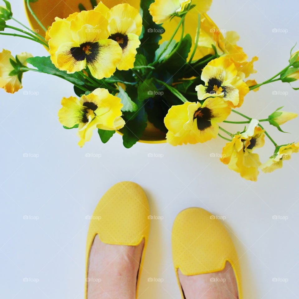 Bright pop of color with yellow flowers and yellow slipper shoes.