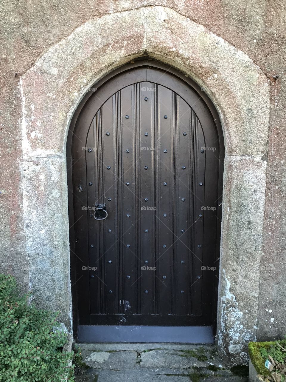 Sumptuous entrance door of Coffinswell’s church, with authentic stone and dark wood veneered door.