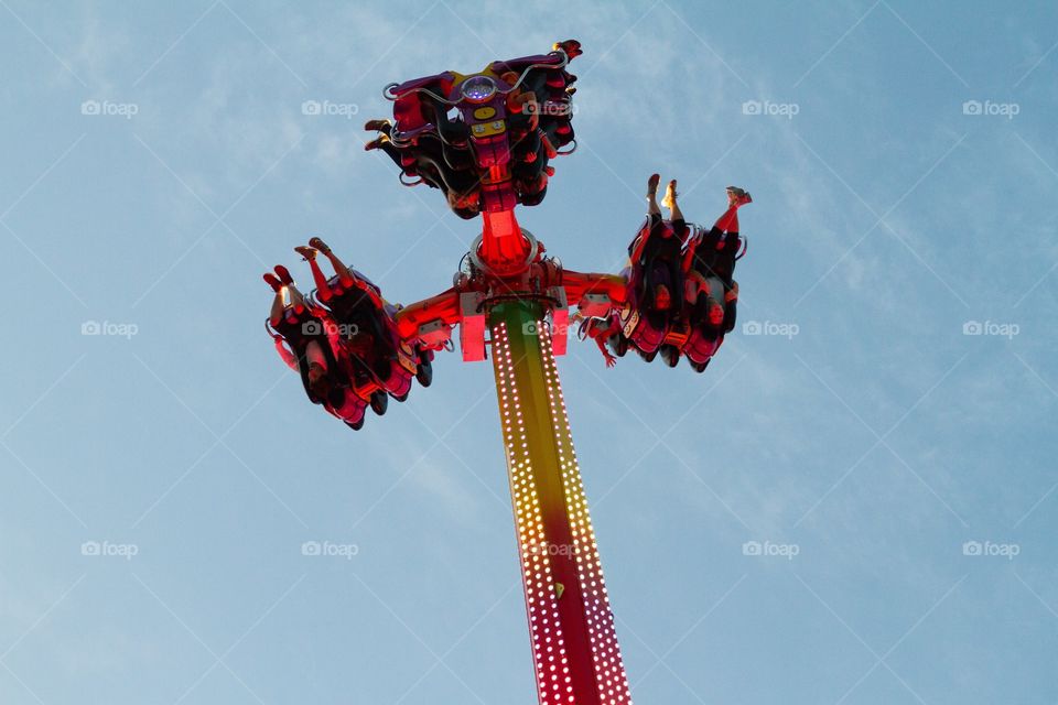 Amusement park ride in upside down position lit up in evening