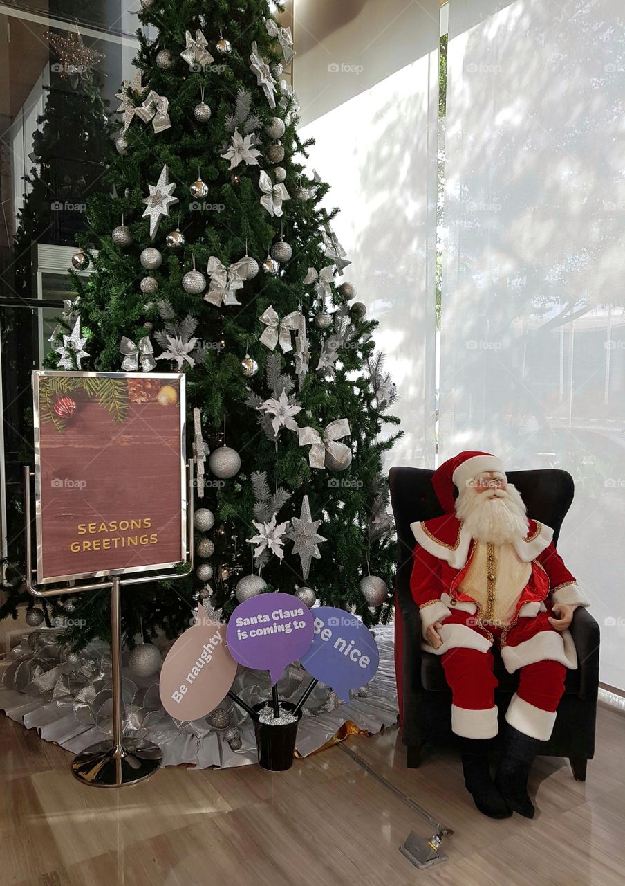 Santa claus sitting by a christmas tree