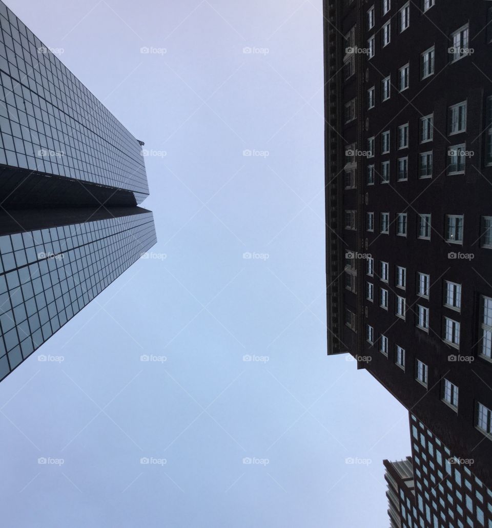 Looking up at the sky in between tall buildings in the city 