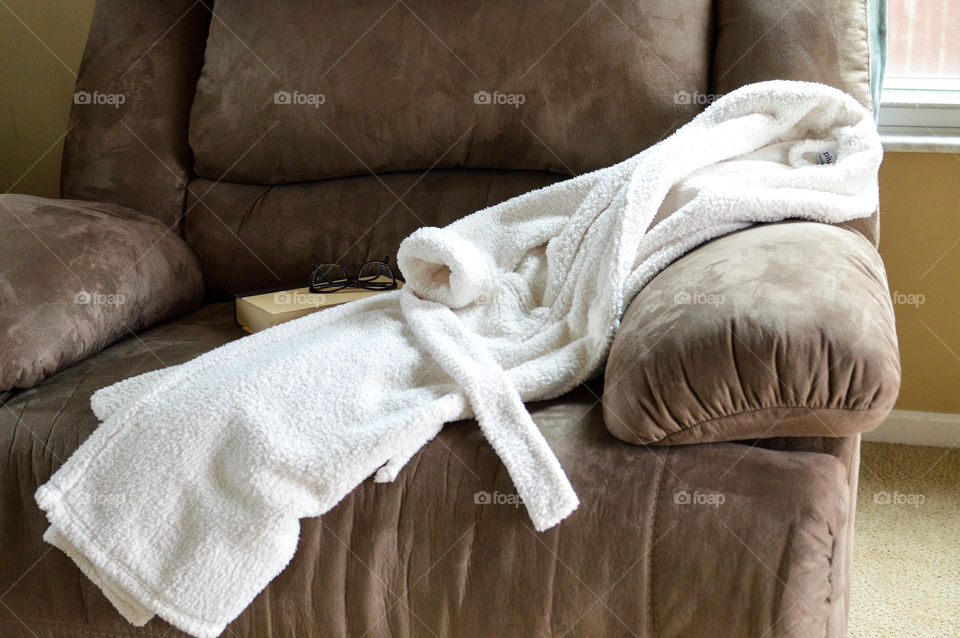 Bathrobe laying on a sofa with a book and glasses