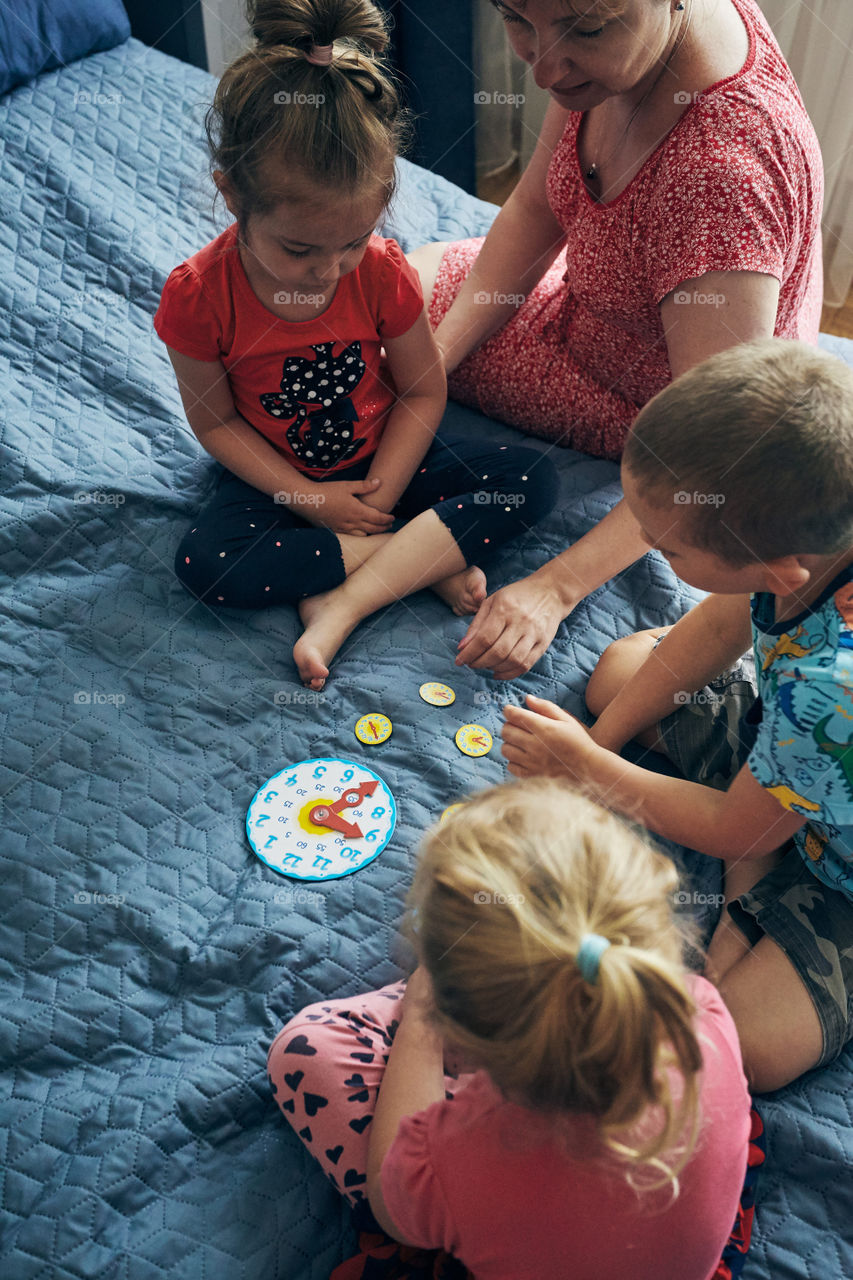 Kids learning how to tell time from clock and set the hands in the correct position. Teaching preschoolers tell time. Candid people, real moments, authentic situations