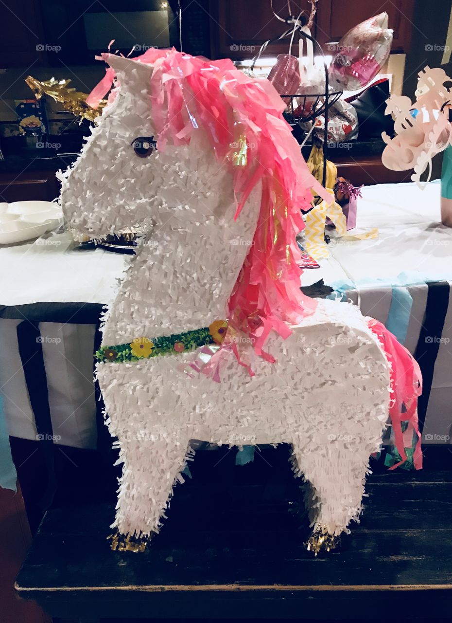 A beautiful and colorful bright pink and white unicorn party piñata on display, celebrating a sweet 16 birthday. USA, America