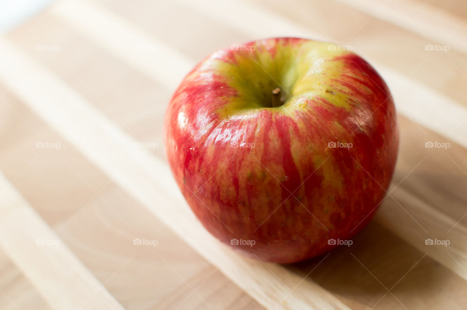 One beautiful red and green apple isolated on wood background studio shot conceptual healthy diet and wellness food photography 