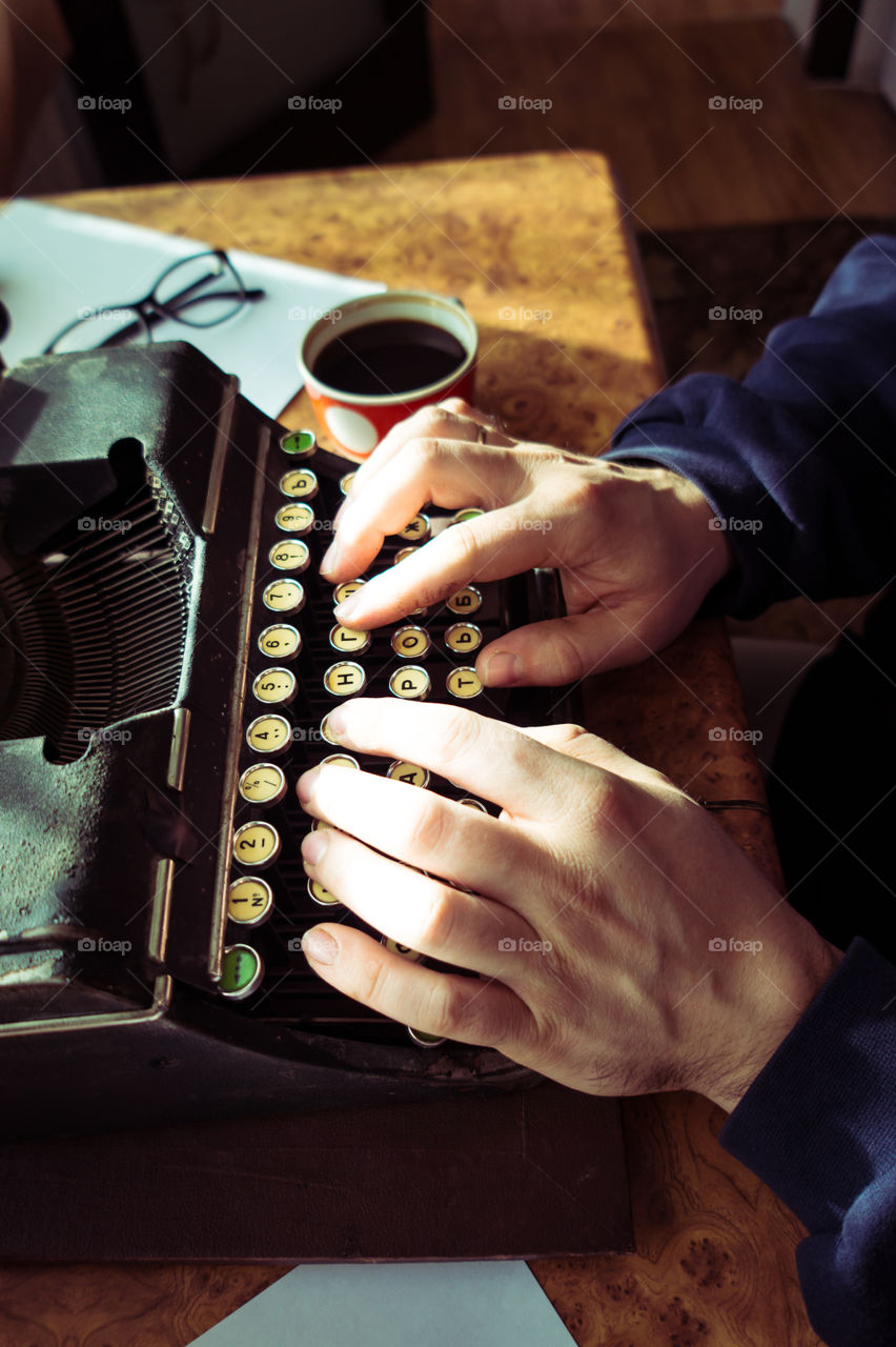 A young writer is writing a new book on an old typewriter.