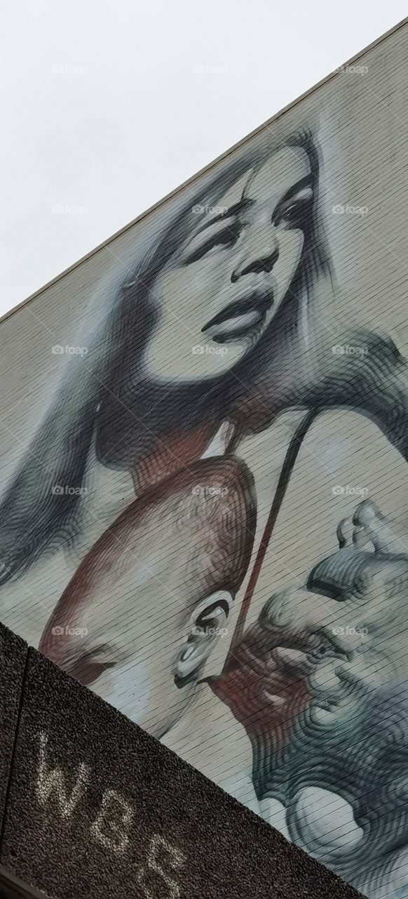 Graffiti de mujer con bebé en lo alto de un edificio