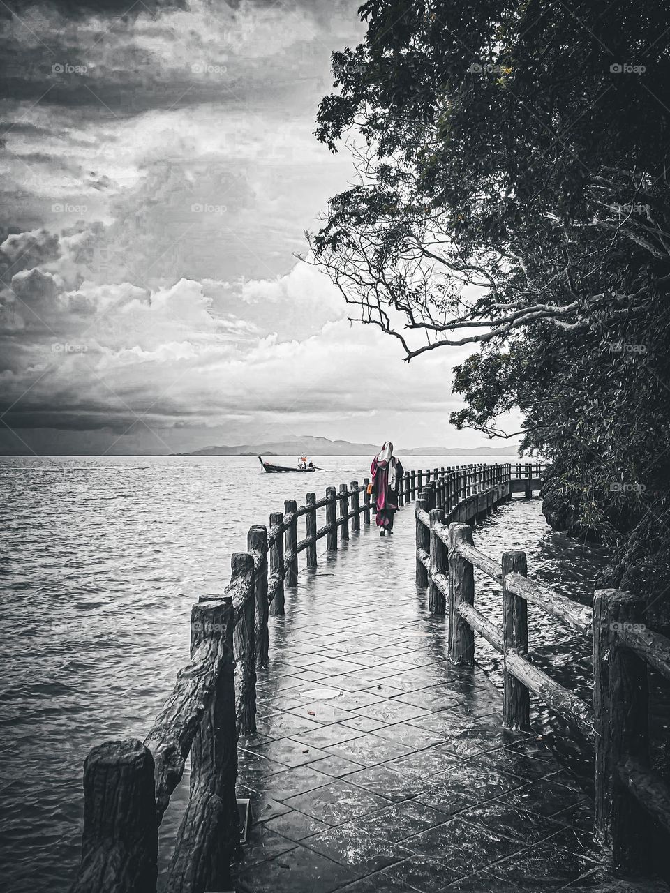 Pathway on the beach and a woman in red dress walking at the end of the pathway