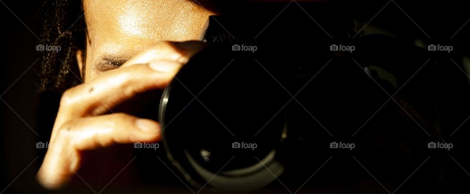 A man takes a picture of himself holding a camera up to his eye.
