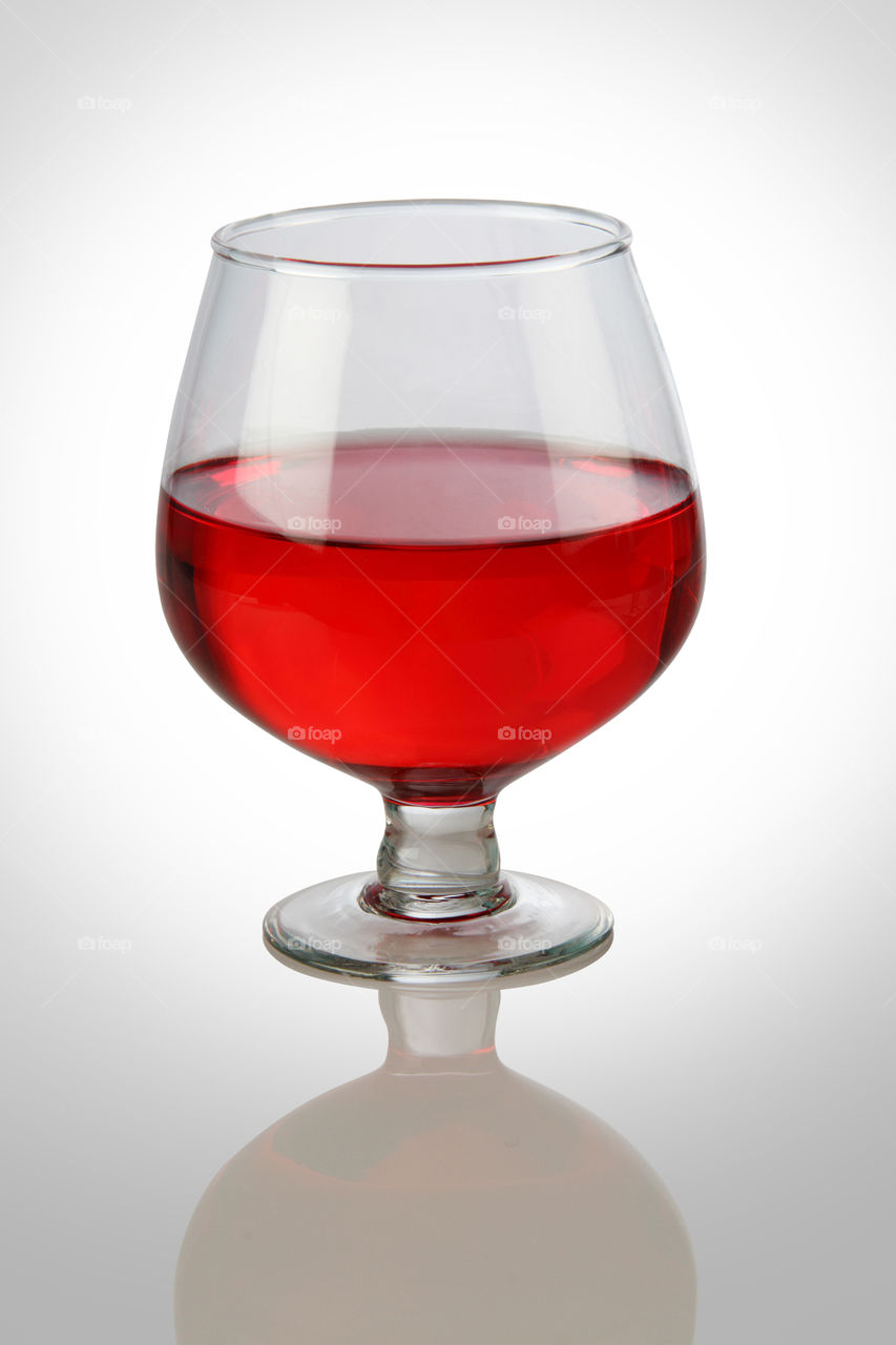 Red wine glass on white reflective background