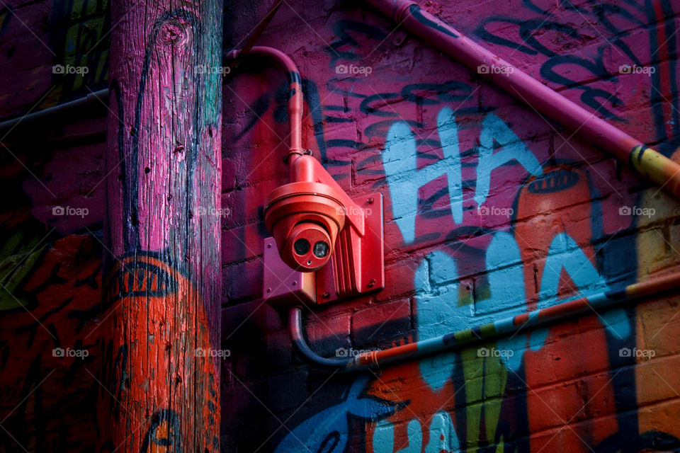 Security camera on a wall with graffiti