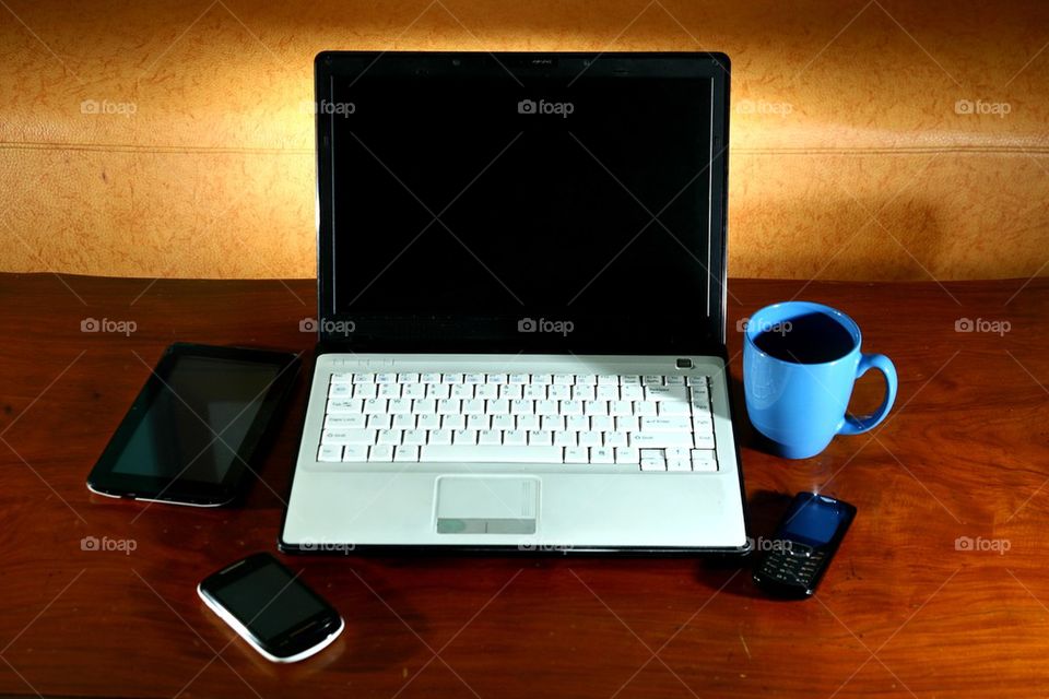 laptop computer, tablet, cellphone, smartphone and a coffee mug on a living room table