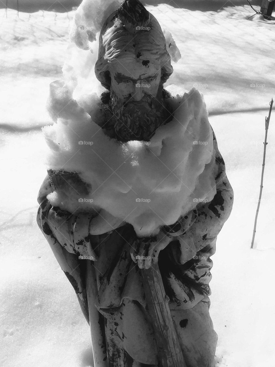 Weathered Saint Francis of Assisi shrouded in snow