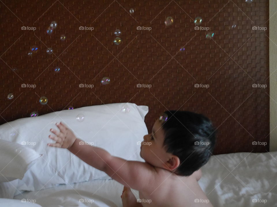 Boy playing with bubbles on bed