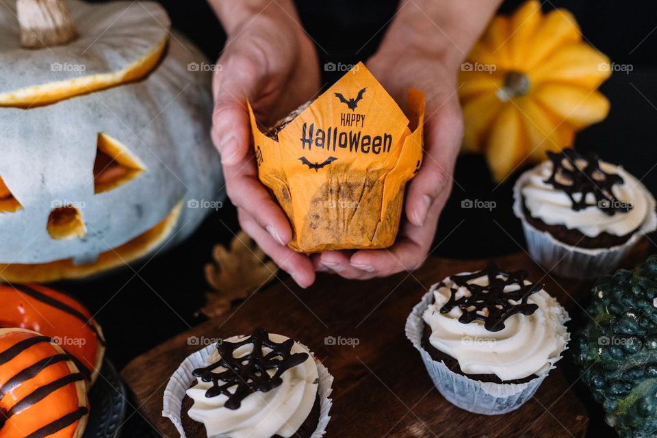 Home made Sweets for the halloween celebration, with chocolate muffins, donuts glazed with orange glaze and a cute carved pumpkin.