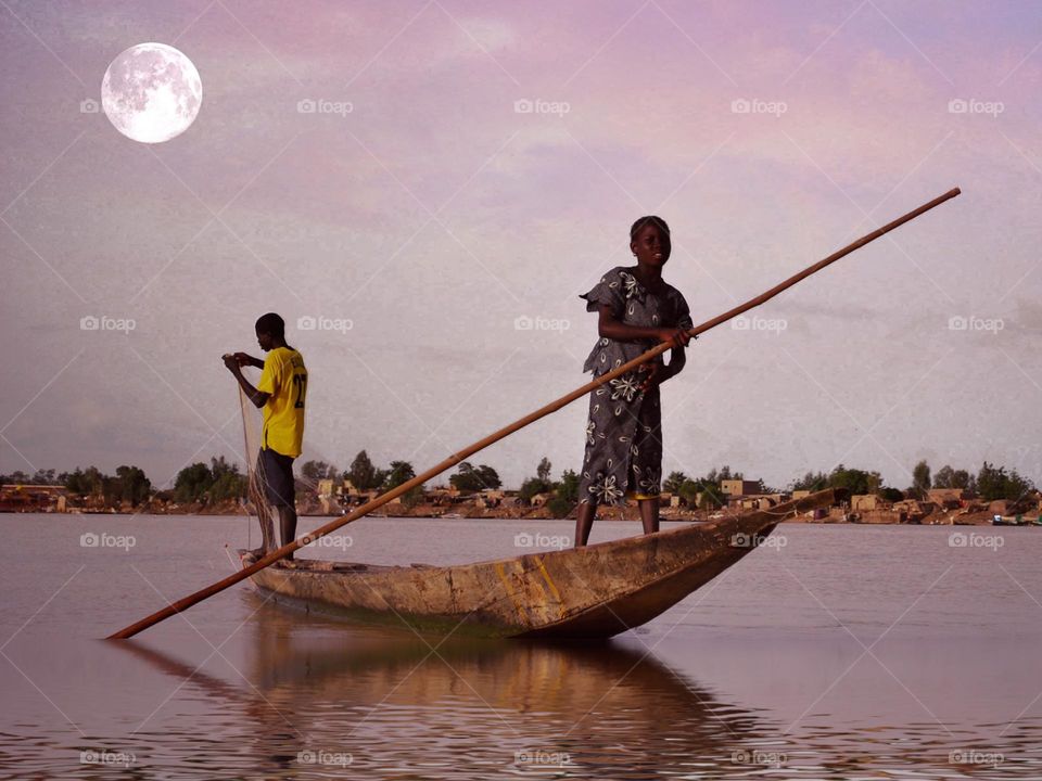 African siblings fishing in traditional fisher boat on the Niger 