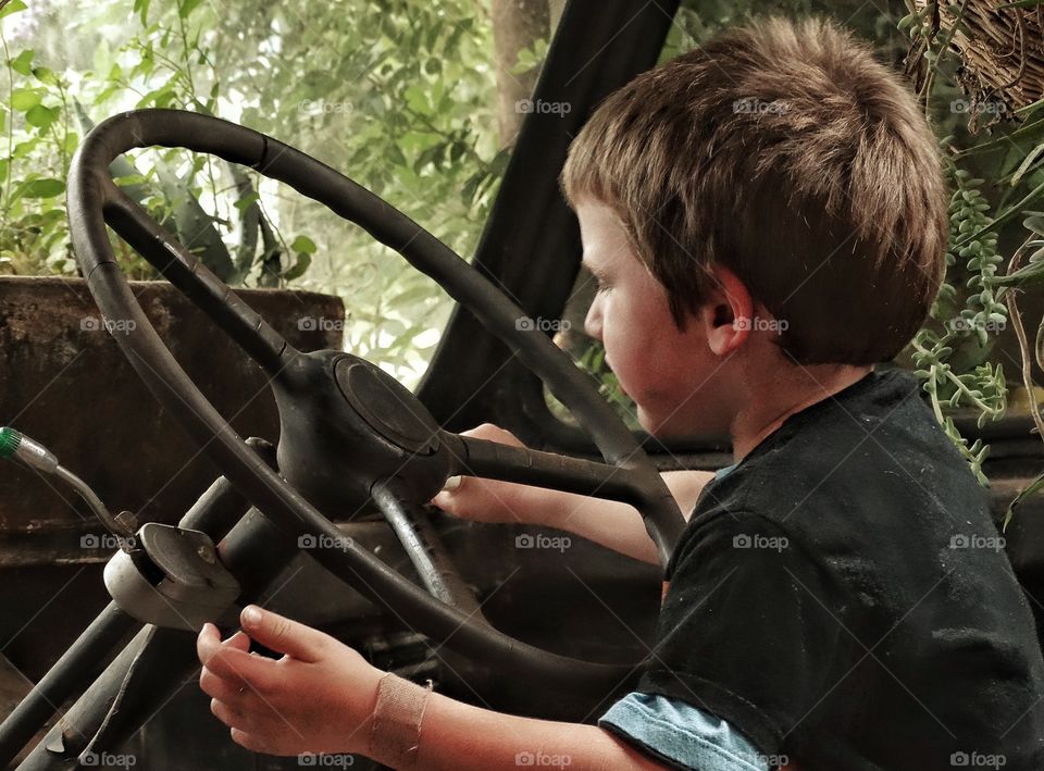 Young Boy Pretending To Drive. Little Boy Playing In A Rusty Old Truck
