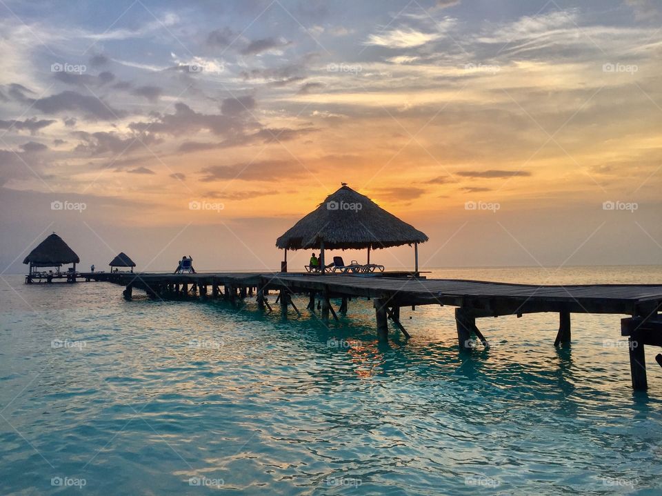 Wooden bridge in sea at sunset