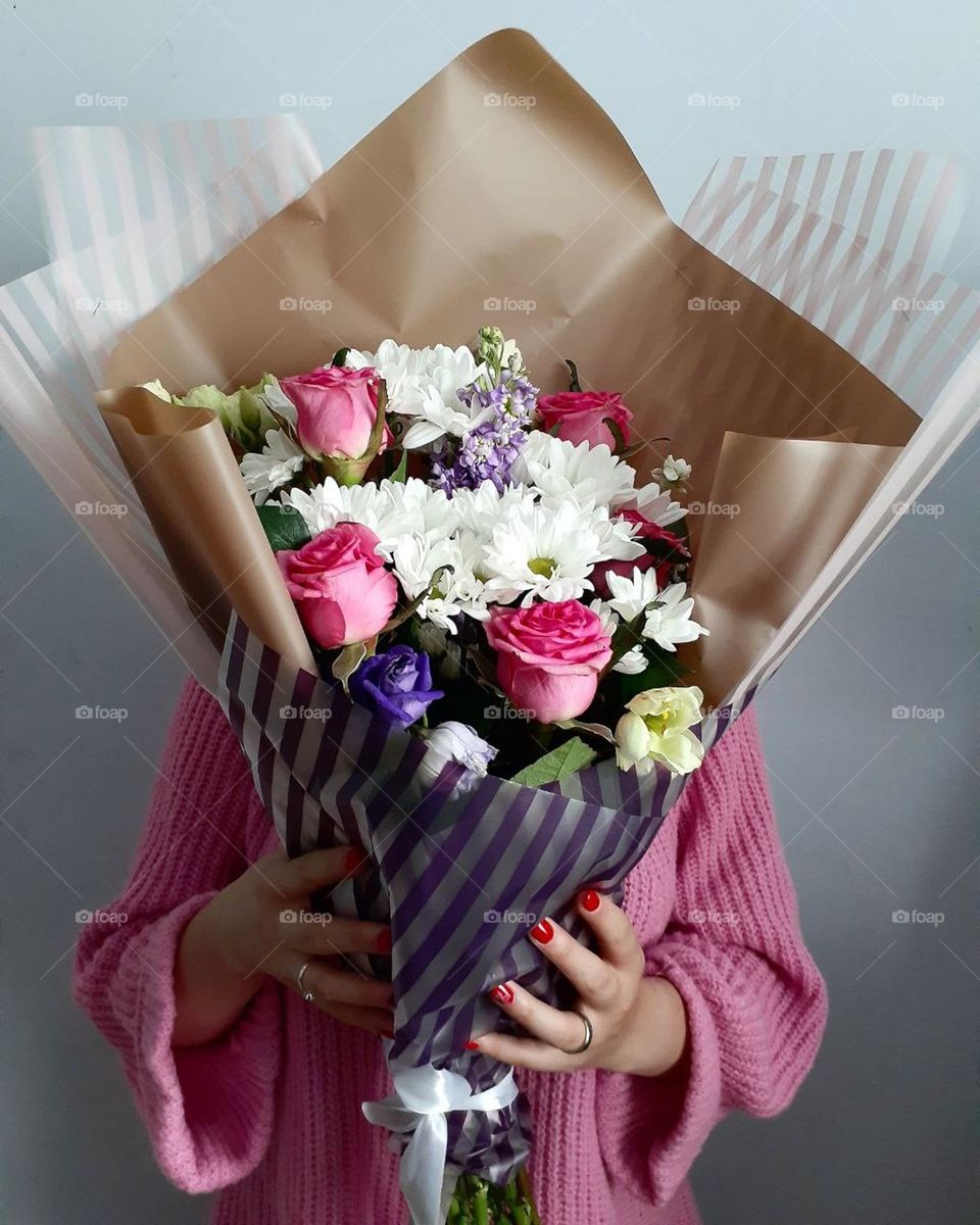 A girl in a pink jacket is holding a bouquet of flowers