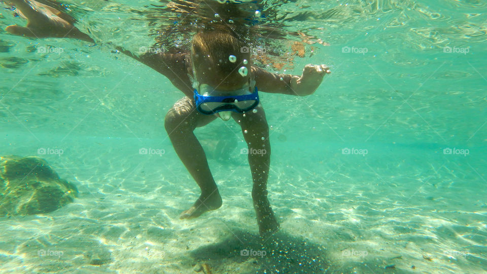 kid diving, male underwater smiling,swimming and exploring in big blue sea