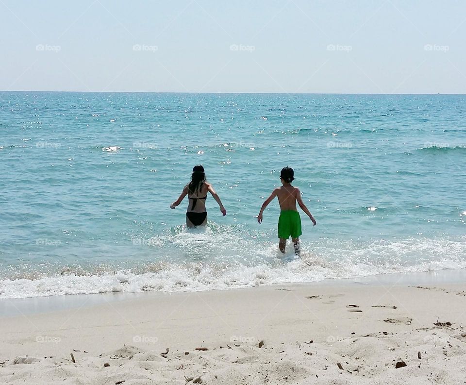 moment of pure happiness at the beach: seeing his children rush to swim in a calm turquoise blue sea.