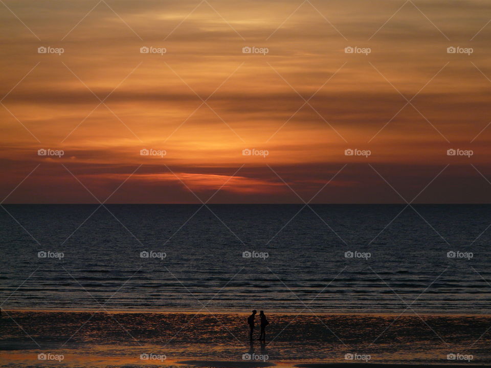 Silhouette of two people at beach at beach during sunset