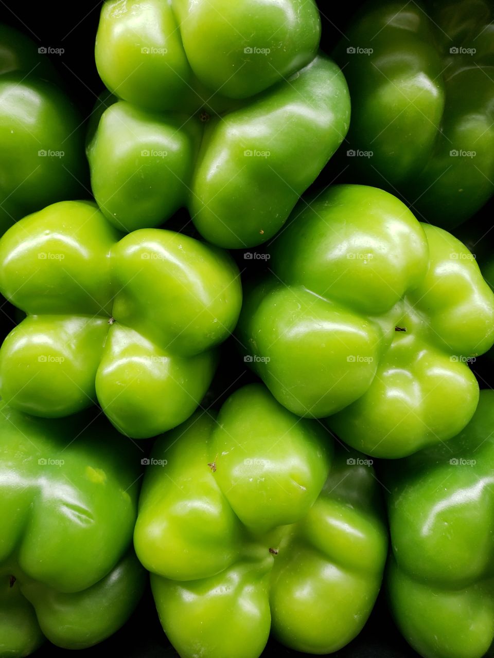 The smooth texture of a pile of green bell peppers
