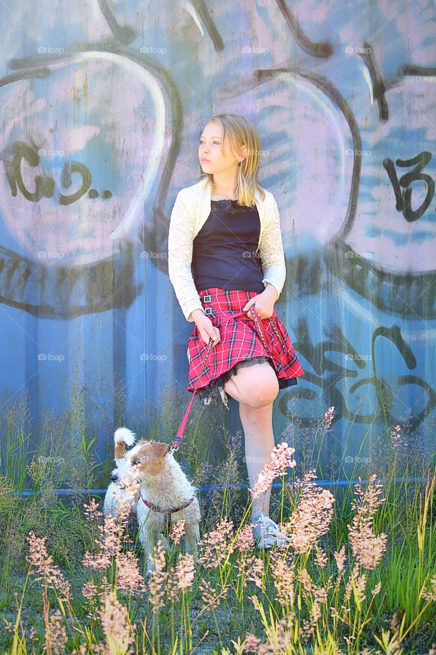 Younger girl standing near painted wall with dog