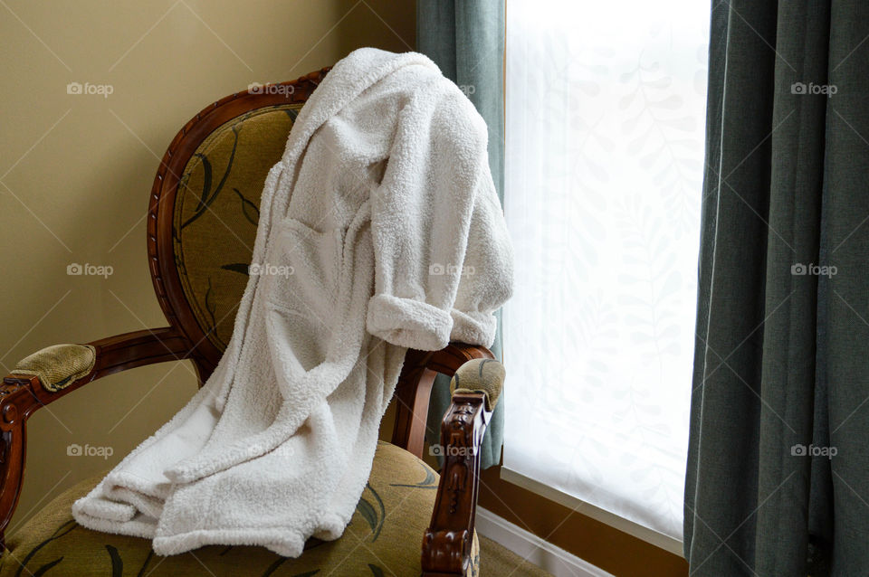 Bathrobe laid out on a chair next to a window