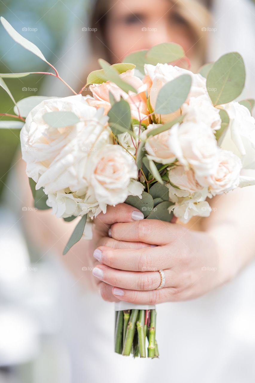 Woman with a wedding band on her finger holding a beautiful bouquet of flowers under natural light