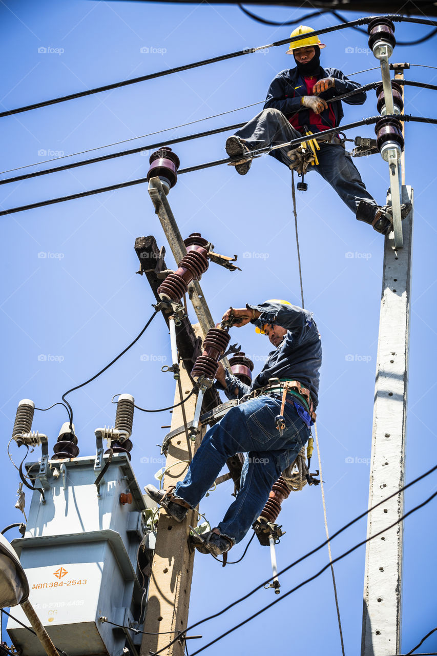 Electrician working together on the electricity pole to replace the electrical insulator