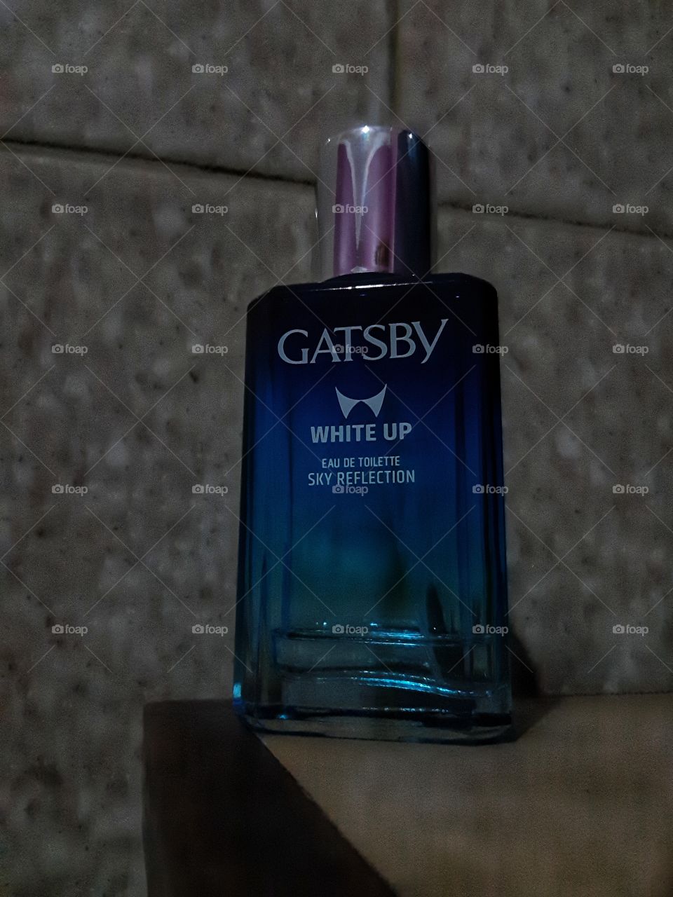 a blue perfume bottle placed on the corner of the table and shot from the bottom angle.