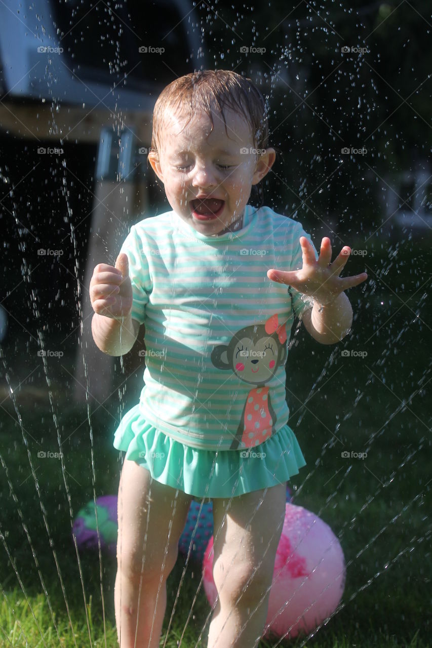 Child playing near garden sprinkler