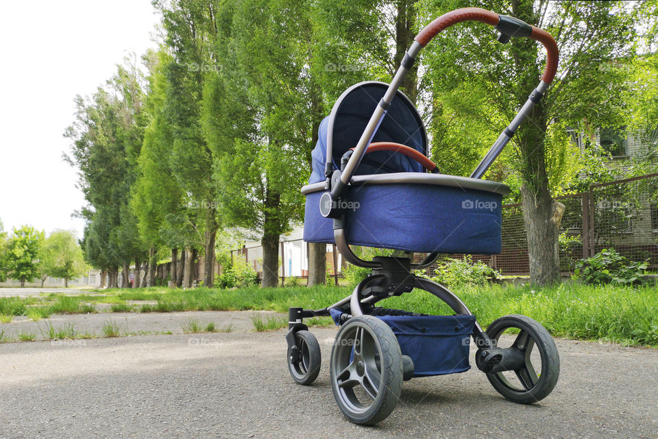 One pram baby in the park on a sunny day. Parent walking with carriage in city park