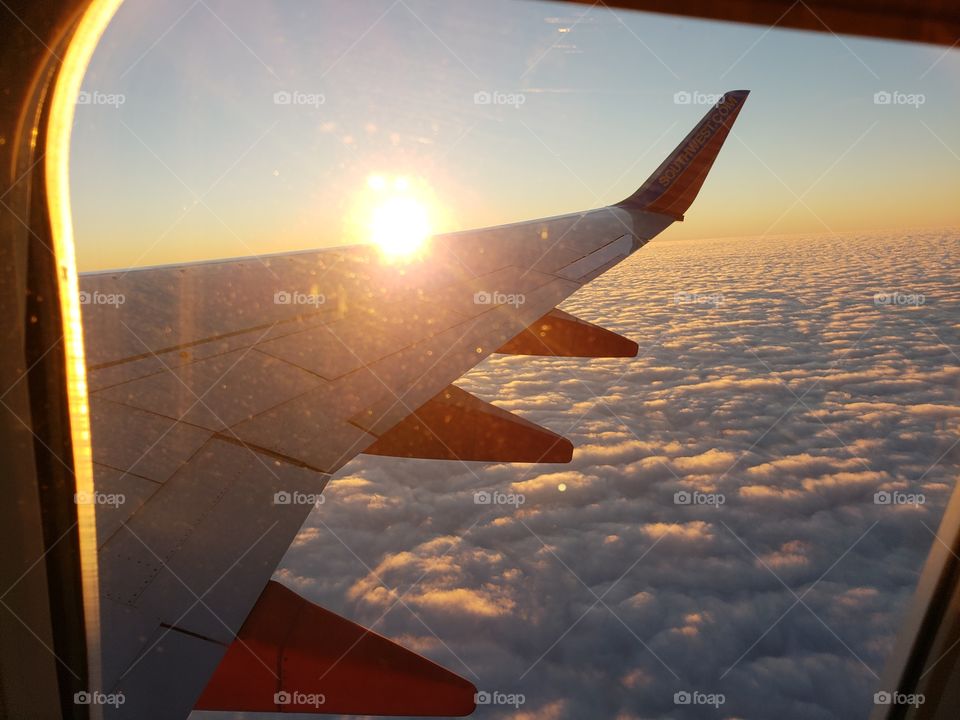 A view from the blanket of clouds with a golden sunset on Southwest Airlines