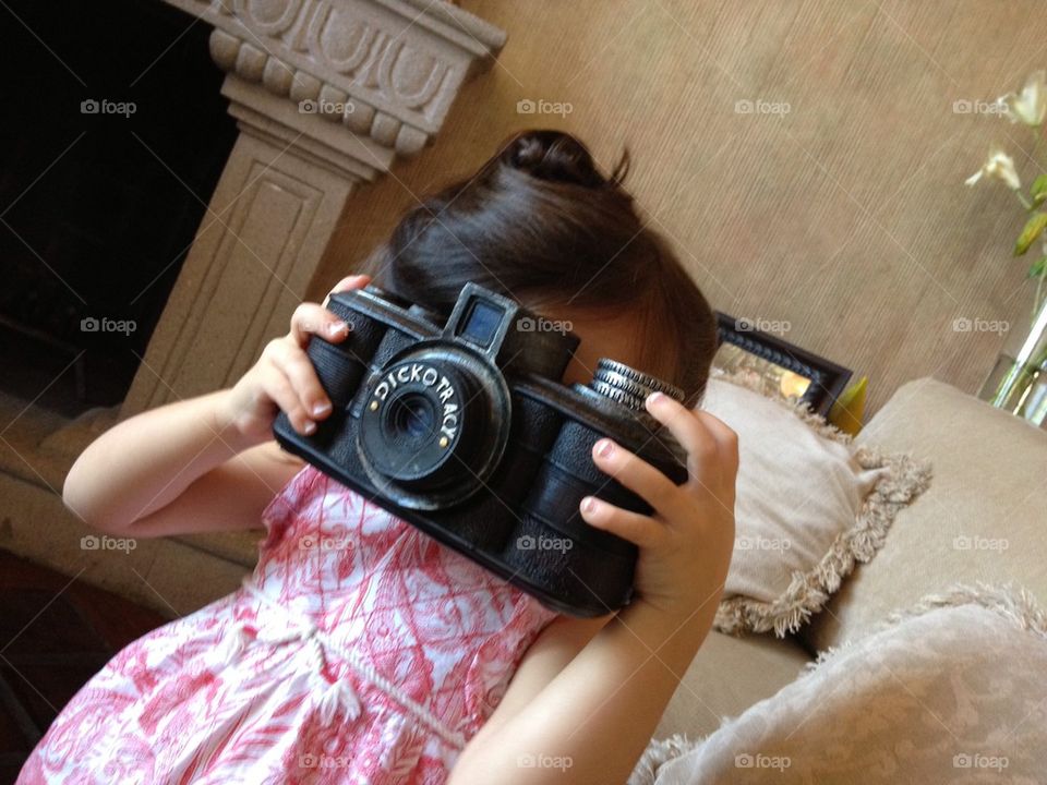 Little girl playing with old giant photo camera