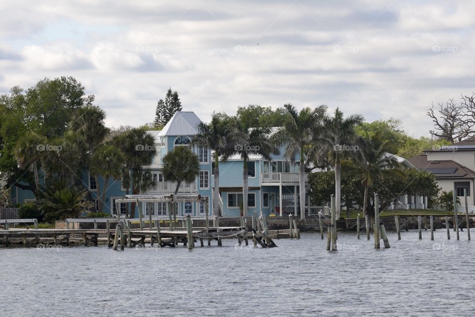 A big blue house on a river with a dock in front